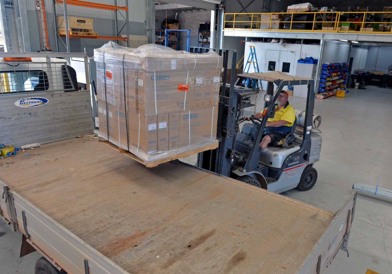 Interior facility with forklift loading electrical components onto flatbed truck.